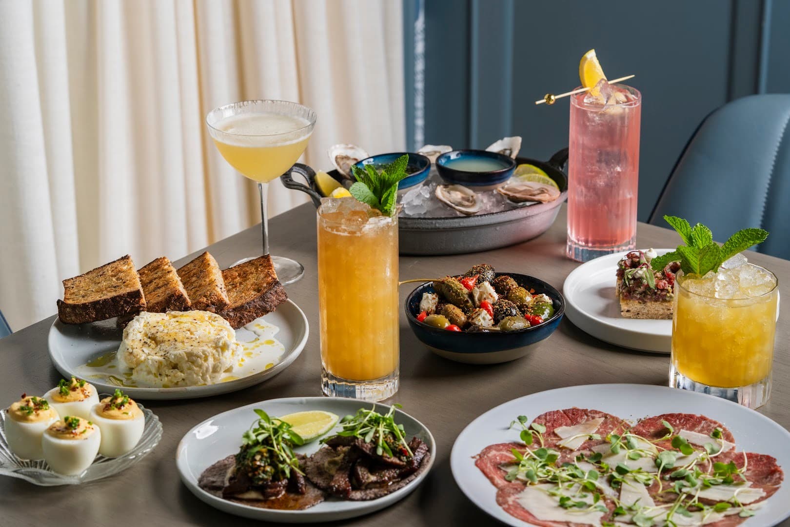 Diverse dining scene at Klaw Miami featuring seafood and cocktails